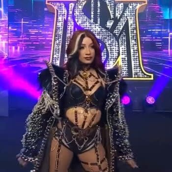 Mercedes Monè stands on the AEW Dynamite stage in an ornate black entrance outfit amid purple and blue lights.