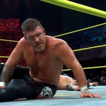 Steve Maclin sits on the mat during a TNA Championship match on Impact, with a referee nearby and the crowd in the background.