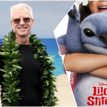 Chris Sanders smiles in a lei beside a Lilo & Stitch promotional image featuring Stitch hugging Lilo.