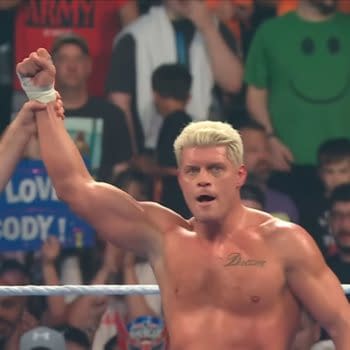 Cody Rhodes stands in the ring with his arm raised in victory after winning a number one contender match on WWE SmackDown. A referee lifts his hand as the crowd watches behind him.