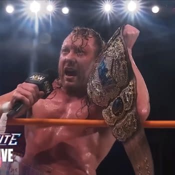 Kenny Omega, sweaty and triumphant, addresses the crowd in the AEW ring while holding the AEW World Championship after winning at Beach Break.