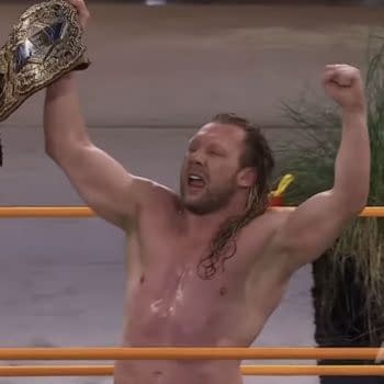 Kenny Omega raises the AEW Championship overhead in celebration after winning the title at Beach Break.