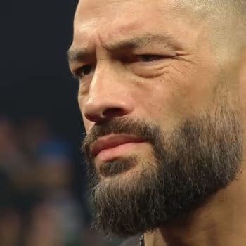 Close-up of Roman Reigns on WWE Raw, looking unimpressed and skeptical. His expression suggests tension in a confrontation with Seth Rollins.