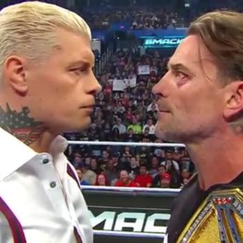 A close-up shot from shoulders up of Cody Rhodes and WWE Champion CM Punk staring face-to-face in the middle of a wrestling ring on WWE SmackDown, the WWE Championship draped over the shoulder of Punk, who has a black eye.