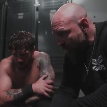 In a dimly lit locker room, Jon Moxley is seen giving advice to Will Ospreay, both mens' faces shrouded in shadow.