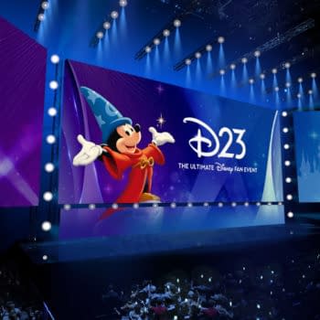 D23 stage at the Honda Center with Mickey Mouse in Sorcerer’s Apprentice costume and a large Disney fan event backdrop, lit in blue and purple.