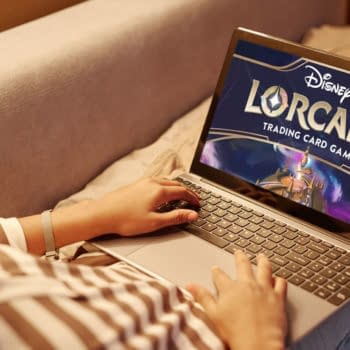 Someone playing the Disney Lorcana trading card game on a laptop while lying in bed at night.