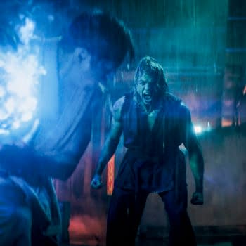 Promotional still from Street Fighter showing two men in a neon-lit alley, one lunging in the foreground while the other screams with clenched fists.