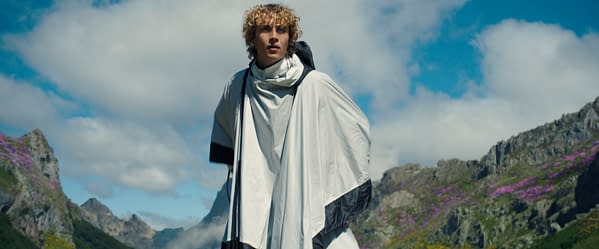 Joseph Zada as Haymitch Abernathy stands in a white cloak against a dramatic mountain landscape in The Hunger Games: Sunrise on the Reaping.