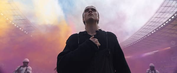 Joseph Zada as Haymitch Abernathy stands in a stadium filled with colorful smoke in The Hunger Games: Sunrise on the Reaping.