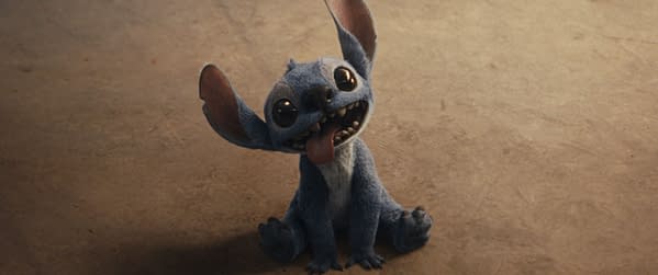 A digital rendering of Stitch, the mischievous blue character from Disney's live-action 'Lilo & Stitch,' sitting on a flat surface with a playful expression, featuring large eyes and oversized ears.