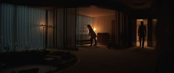 A scene from 'The Fantastic Four: First Steps' featuring Vanessa Kirby as Sue Storm near a crib in a softly lit room, with Pedro Pascal as Reed Richards silhouetted in the doorway.