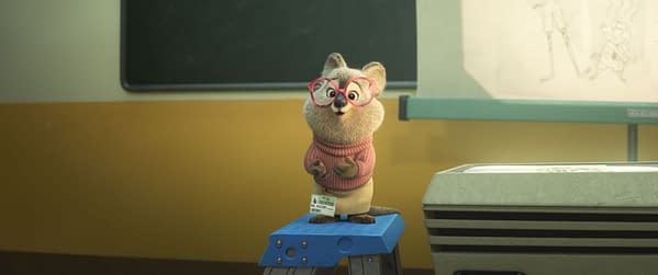 An animated cartoon character, Dr. Fuzzby, a quokka with glasses, stands on a blue stool in a classroom setting, wearing a pink sweater and holding a visitor badge. This character appears in Disney's "Zootopia 2," where they assist the detectives Nick Wilde and Judy Hopps.