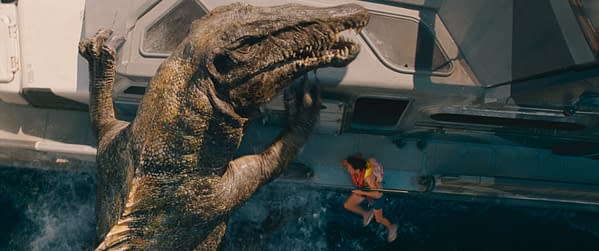 A dramatic scene from 'Jurassic World Rebirth' shows a large dinosaur reaching towards a person in a life jacket who is attempting to escape. The setting is on a boat in water, emphasizing a tense moment of danger.