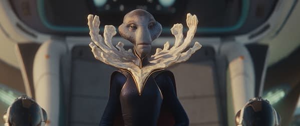 A futuristic alien character, the Grand Councilwoman, portrayed by Hannah Waddingham in Disney's live-action 'Lilo & Stitch', stands prominently with a unique coral-like headpiece and a dark costume, set against a high-tech background.