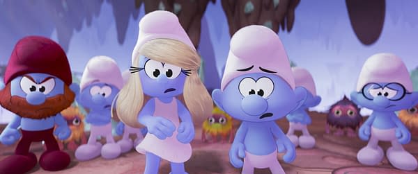 A scene from the animated movie "Smurfs," featuring the characters Smurfette, Brainy Smurf, and Ken. Smurfette has blonde hair and a worried expression, while Brainy Smurf looks concerned, set against a colorful background with other Smurf characters in the scene.