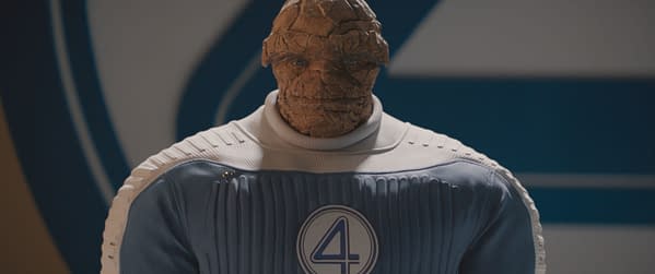 Ebon Moss-Bachrach portrays Ben Grimm, also known as The Thing, in a blue and white superhero suit featuring the number four emblem, from the Marvel Studios film "The Fantastic Four: First Steps." The character has a textured, rocky appearance.