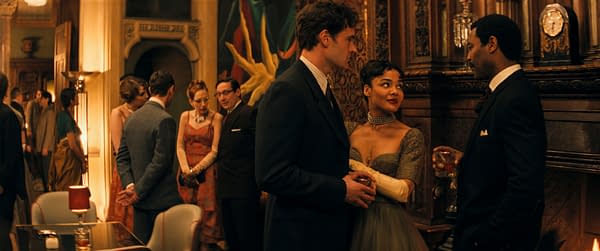 A scene from the play "Hedda" featuring characters George Tessman, Hedda Gabler, and Judge Roland Brack engaged in conversation at a social gathering, with elegant decor in the background.