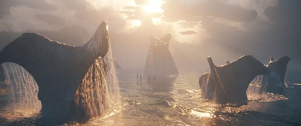 A scene from 'AVATAR: FIRE AND ASH' featuring towering rock formations with waterfalls cascading into a tranquil body of water, illuminated by a glowing sunset. Silhouetted figures can be seen near the water's edge, creating a mystical and serene atmosphere.