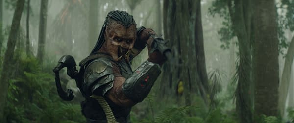 An alien character with distinct features, wearing armor and wielding a weapon, is set against a misty forest background, representing the film Predator: Badlands.
