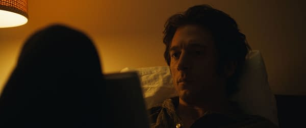 Jeremy Allen White portrays Bruce Springsteen in a scene from 20th Century Studios' film 'SPRINGSTEEN: DELIVER ME FROM NOWHERE,' captured in a dimly lit room with soft, warm tones.