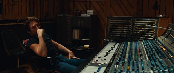 Jeremy Allen White portrays Bruce Springsteen, seated in a recording studio, deep in thought as he observes a large sound mixing console filled with colorful knobs and faders. The scene captures a reflective moment from the film 'SPRINGSTEEN: DELIVER ME FROM NOWHERE'.
