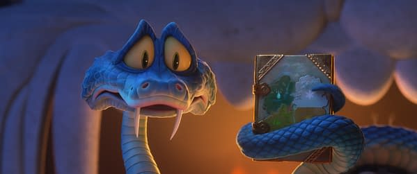 In this cartoon scene from 'Zootopia 2,' Gary De'Snake, a blue anthropomorphic snake with large, expressive eyes, holds a book displaying a colorful landscape. The setting conveys a whimsical atmosphere, characteristic of Disney Animation.