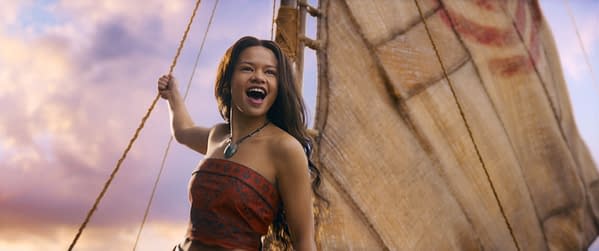 Catherina Laga'aia plays Moana in a promotional image from Disney's live-action adaptation, showcasing her joy as she stands on a boat against a colorful sky.