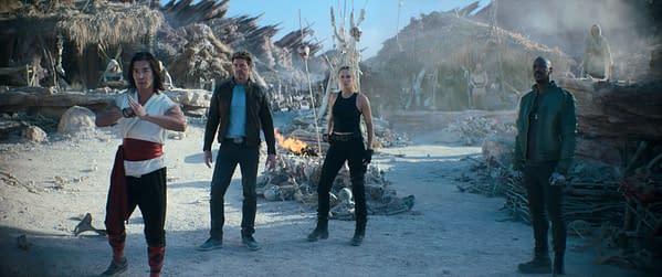 A scene from 'Mortal Kombat II' featuring four characters in a desolate, rocky landscape, with remnants of a campfire and skeletal remains in the background. The characters appear ready for a confrontation, exuding a sense of tension and anticipation.