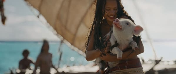 In Disney's live-action adaptation of Moana, Catherine Laga'aia as Moana joyfully holds a pig named Pua against a scenic backdrop of the ocean and a sailboat. The scene captures a moment of companionship and adventure.