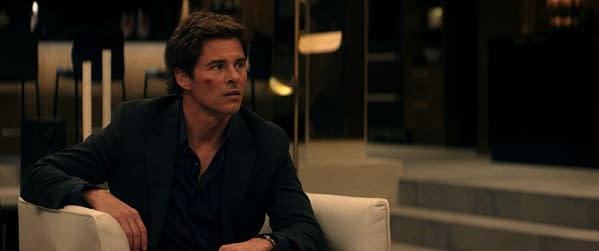 A scene from the film 'Mike & Nick & Nick & Alice' featuring James Marsden as Mike, looking concerned with a faint mark on his cheek, seated in a modern setting with stylish furniture.