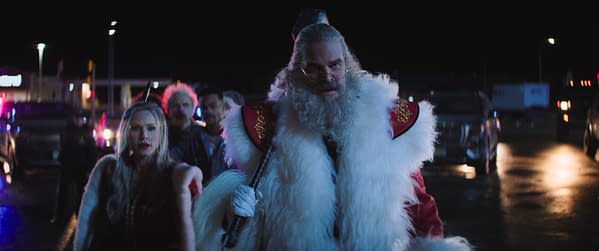 Mrs. Claus and Santa Claus stand in a dark, neon-lit scene with other figures behind them in Violent Night 2.