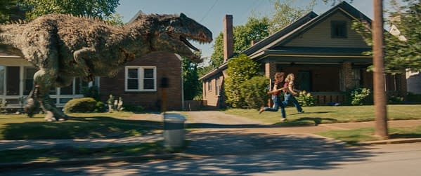 A giant dinosaur chases two children running past suburban houses on a tree-lined street.