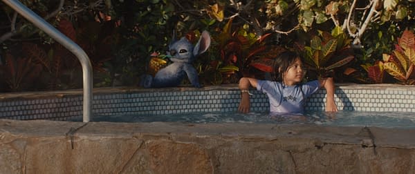 A scene from Disney's live-action 'Lilo & Stitch' featuring Maia Kealoha as Lilo relaxing in a hot tub with Stitch, who is holding a fruity drink. The background is filled with vibrant tropical foliage.