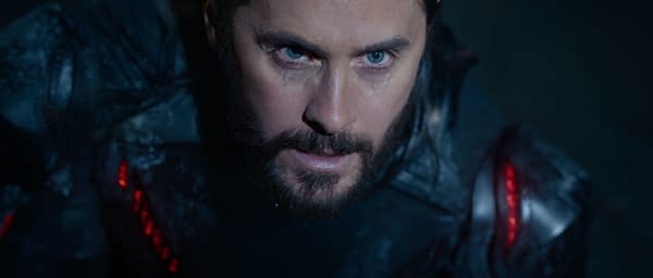 Jared Leto portrays Ares in a close-up shot from Disney's live-action film TRON: ARES, featuring dramatic lighting and a futuristic costume with red accents.