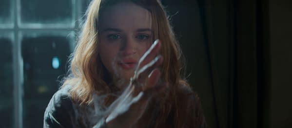 A young woman with long, wavy hair is looking intently at her hand, which is shrouded in mist or smoke, suggesting magical or mystical themes. The ambient light creates a dramatic atmosphere, enhancing the sense of enchantment.