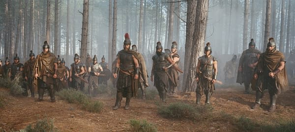 Matt Damon as Odysseus leads a group of armored warriors through a misty forest in The Odyssey.