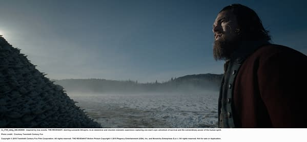 A still from the film THE REVENANT featuring a man with a beard and long hair, standing in a snowy landscape, gazing towards the horizon. The scene conveys a sense of survival and the harshness of nature.