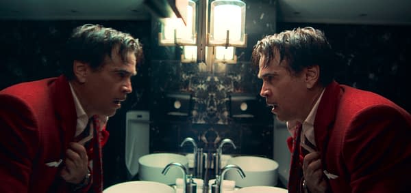Ballad of a Small Player A man in a red suit looks intently into a mirror in a bathroom, showing a distressed expression. The background features dark marble walls and modern fixtures.