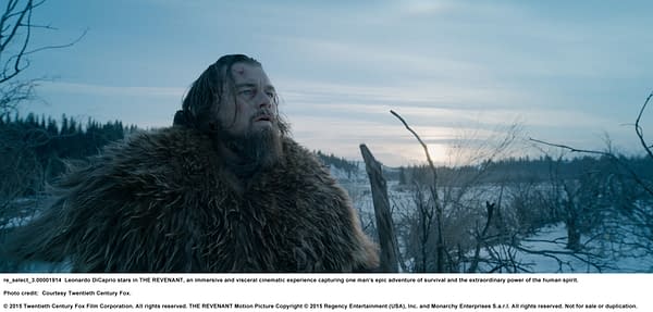 A scene from the film 'THE REVENANT' featuring a rugged man with a beard and long hair, dressed in a fur coat, looking towards a snowy landscape under a cloudy sky. The image captures a moment of solitude and survival.