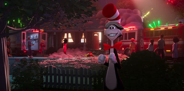 The Cat in the Hat stands in a suburban yard at night, smiling in front of fire trucks and emergency responders. Pink smoke and scattered debris surround the house, creating a chaotic scene.
