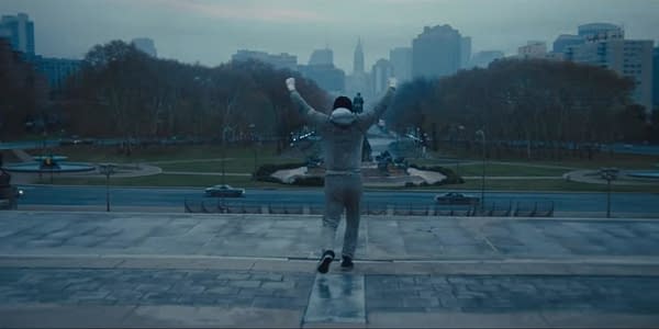 A lone boxer in gray sweats runs up the Rocky Steps with arms raised, overlooking Philadelphia's skyline at dawn.
