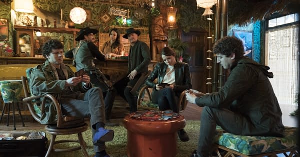 Zombie apocalypse survivors Columbus, Wichita, and Flagstaff turn Magic: The Gathering cards sideways in Zombieland: Double Tap (2019), while Tallahassee, Albuquerque, and Nevada look on. (Image attributed to Columbia Pictures)