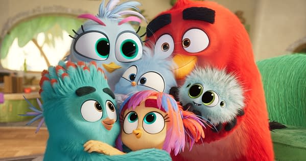 The Angry Birds Movie 3 characters Red and Silver cuddle their three chicks and a fluffy pet in a warm family group hug.