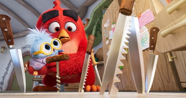 Red holds a small blue chick in a kitchen filled with oversized knives, from The Angry Birds Movie 3.