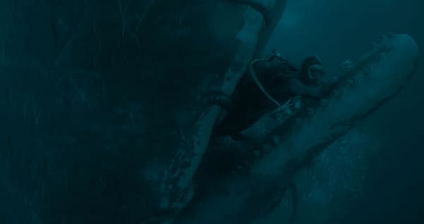 Austin Abrams as Jay Gardiner is submerged in dark blue water beside a giant whale in WHALEFALL.