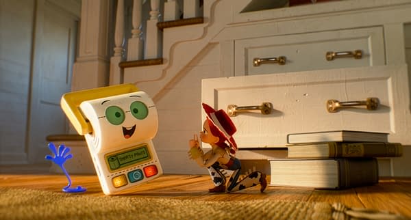 In this scene from Toy Story 5, Jessie interacts playfully with Smarty Pants, a toy that resembles a friendly learning device, on a wooden floor surrounded by books. The image conveys a sense of fun and adventure typical of Pixar's animated films.