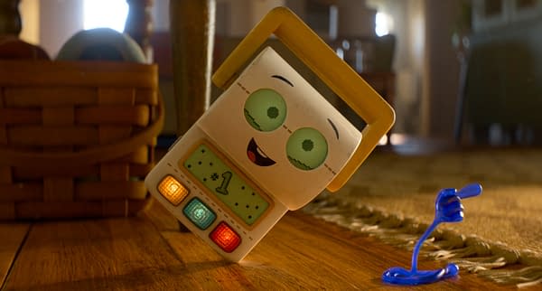 Smarty Pants, a smiling cube-shaped toy from Toy Story 5, leans playfully beside a blue toy figure on a wooden floor.
