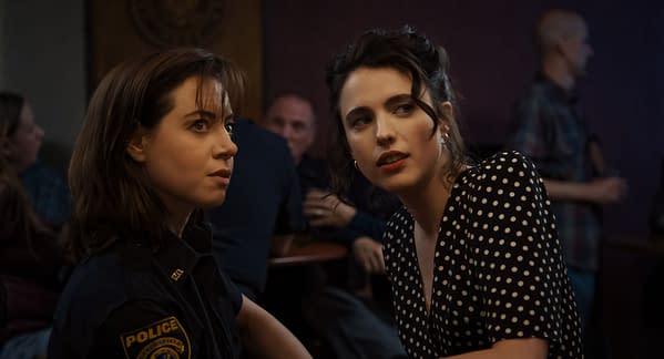 A scene from the film 'Honey Don't!' featuring Aubrey Plaza as MG Falcone and Margaret Qualley as Honey O'Donahue, both looking concerned while seated in a lively bar setting.