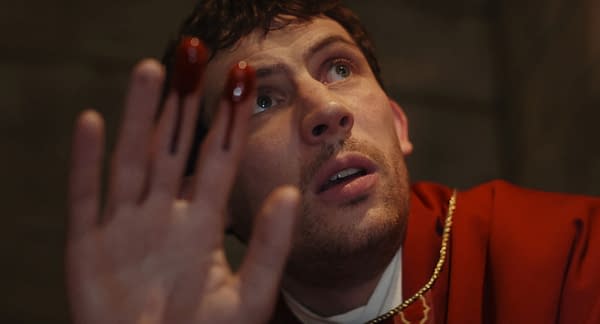 A scene from 'Wake Up Dead Man: A Knives Out Mystery', featuring Josh O'Connor with a shocked expression, holding up a hand with red liquid dripping from his fingers, suggesting a tense and dramatic moment.